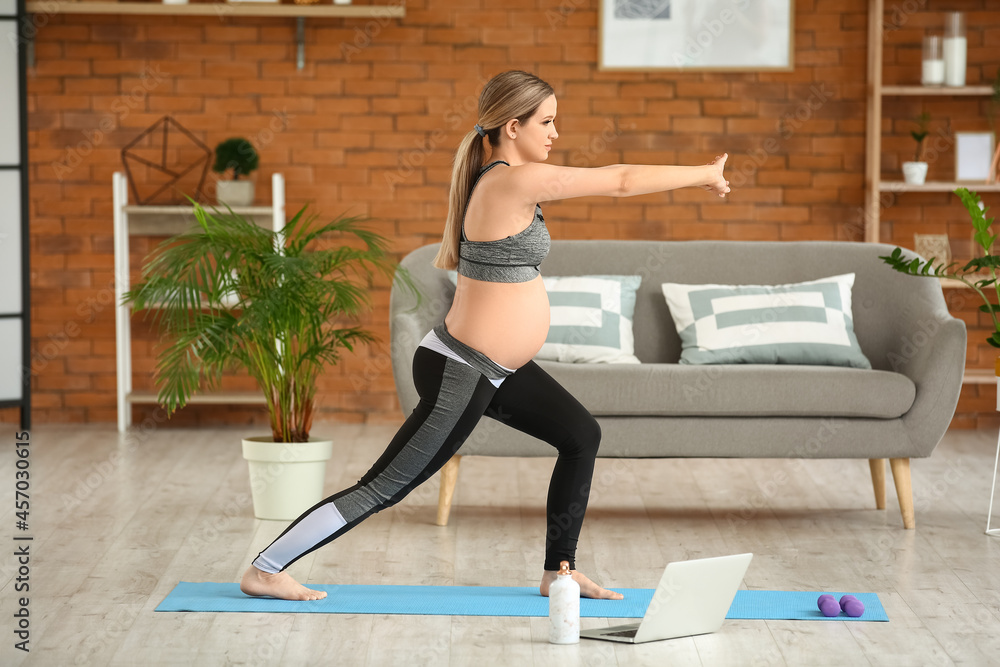 Young pregnant woman practicing yoga at home