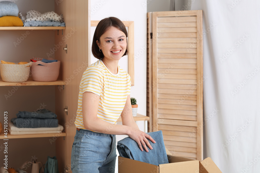 Young woman arranging clothes at wardrobe