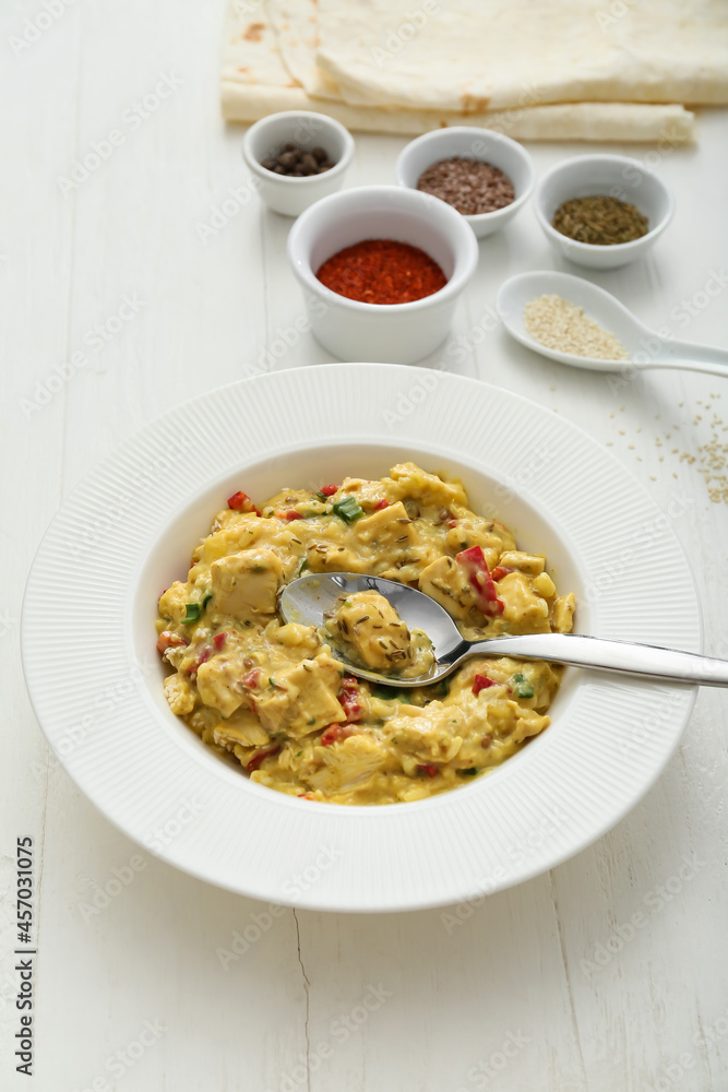 Plate of tasty chicken curry on light wooden background