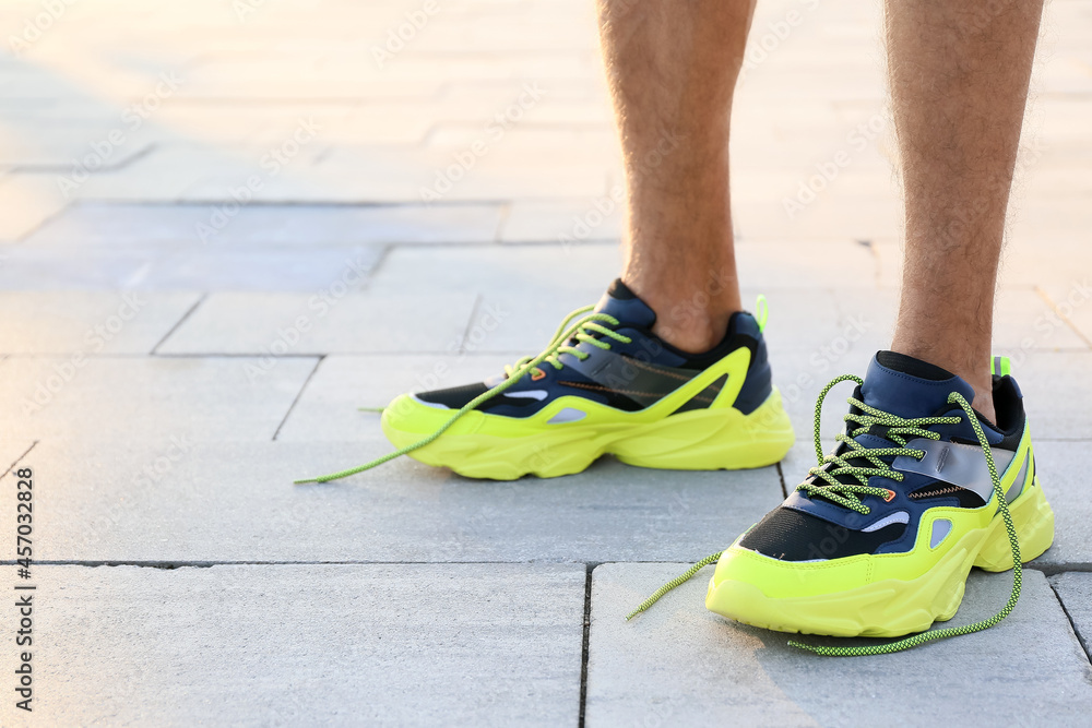 Sporty young man with undone shoe laces outdoors