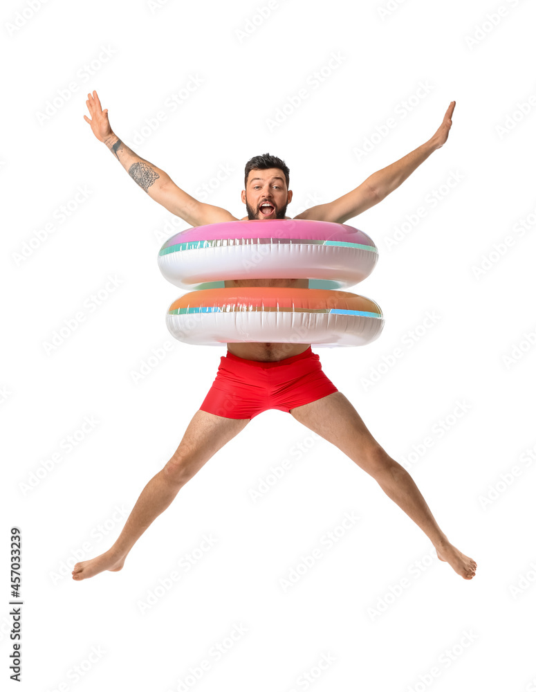 Jumping young man with inflatable rings on white background