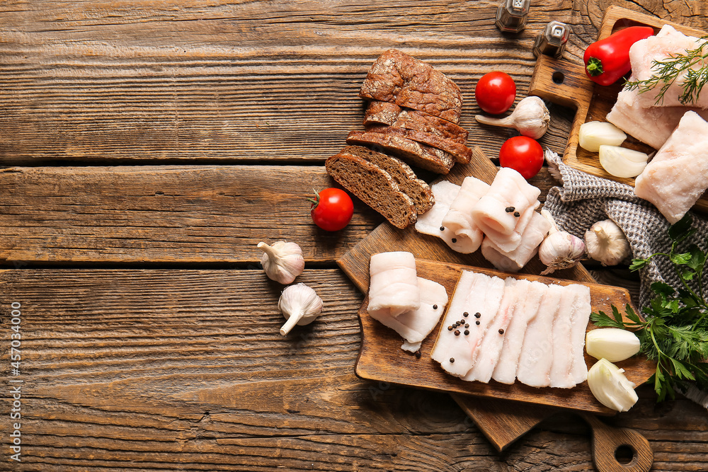 Board with salted lard, bread and fresh vegetables on wooden background