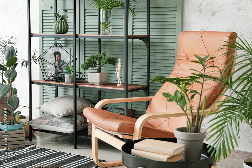 Interior of modern room with stylish armchair, shelves and folding screen