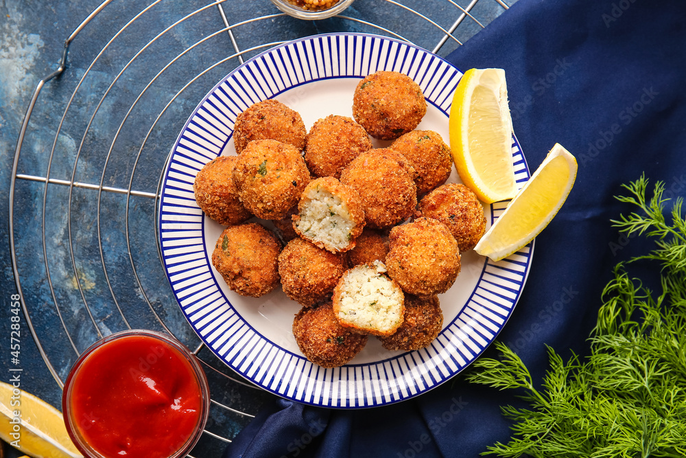 Plate with tasty cod cutlets and sauce on color background