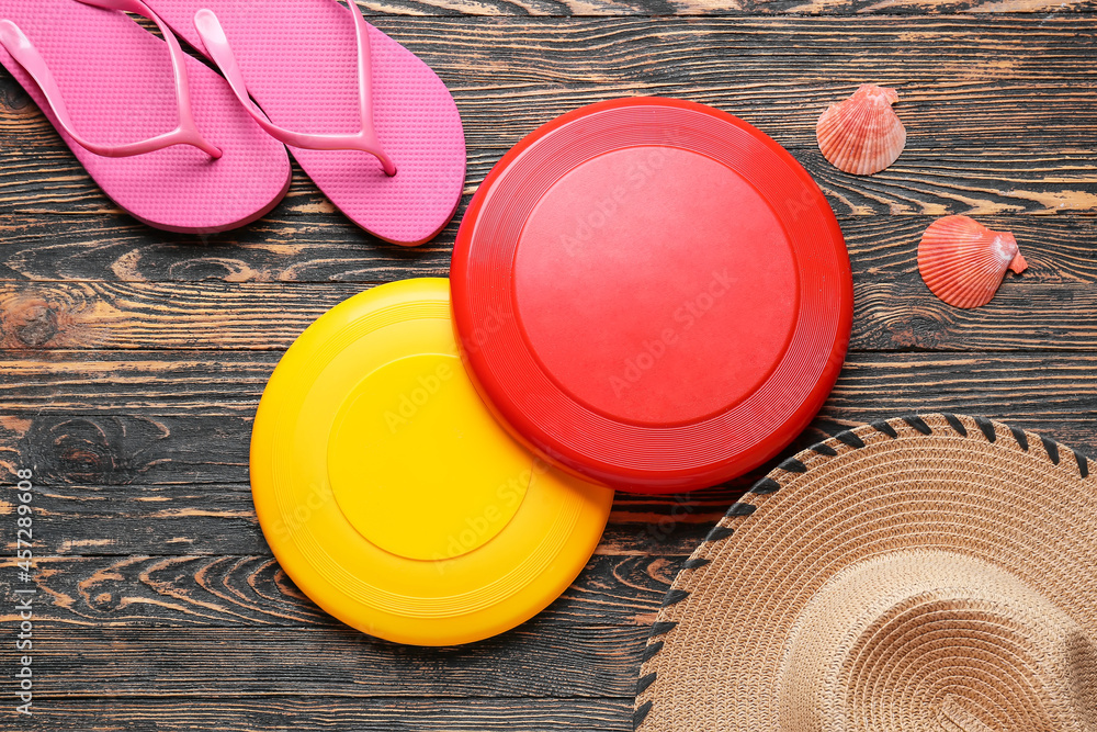 Frisbee disks, hat and flip-flops on wooden background