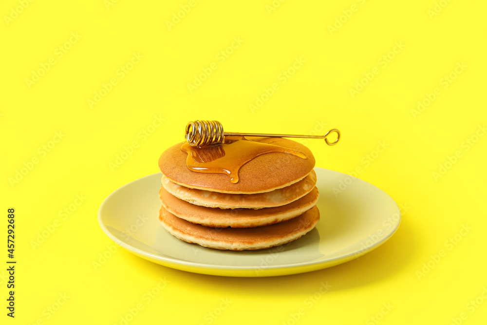 Plate of tasty pancakes with honey on color background