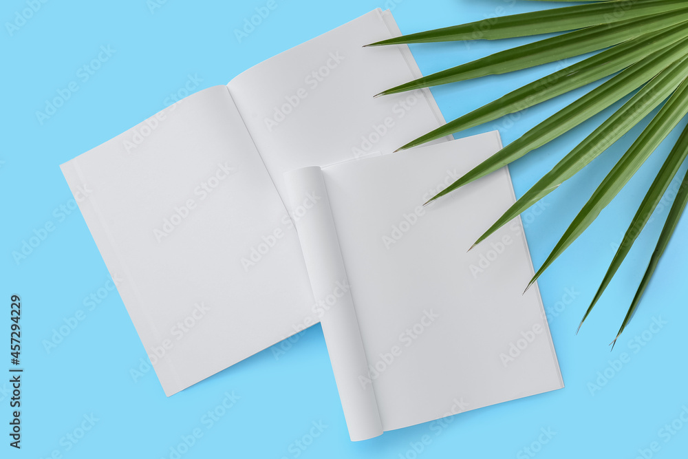 Blank magazines with tropical leaf on color background