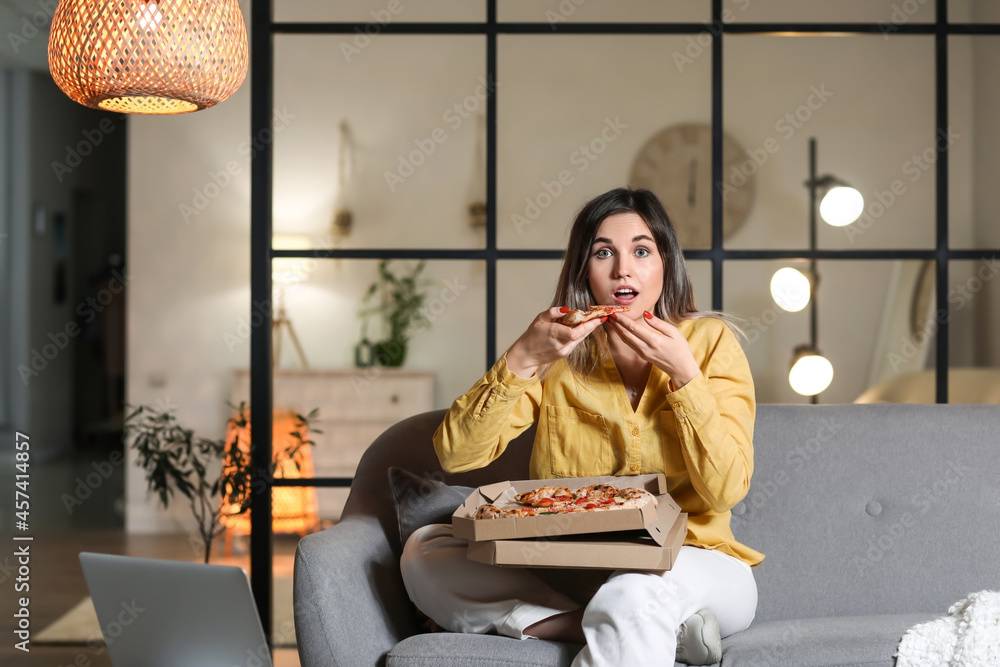 惊讶的年轻女子晚上在家吃美味的披萨