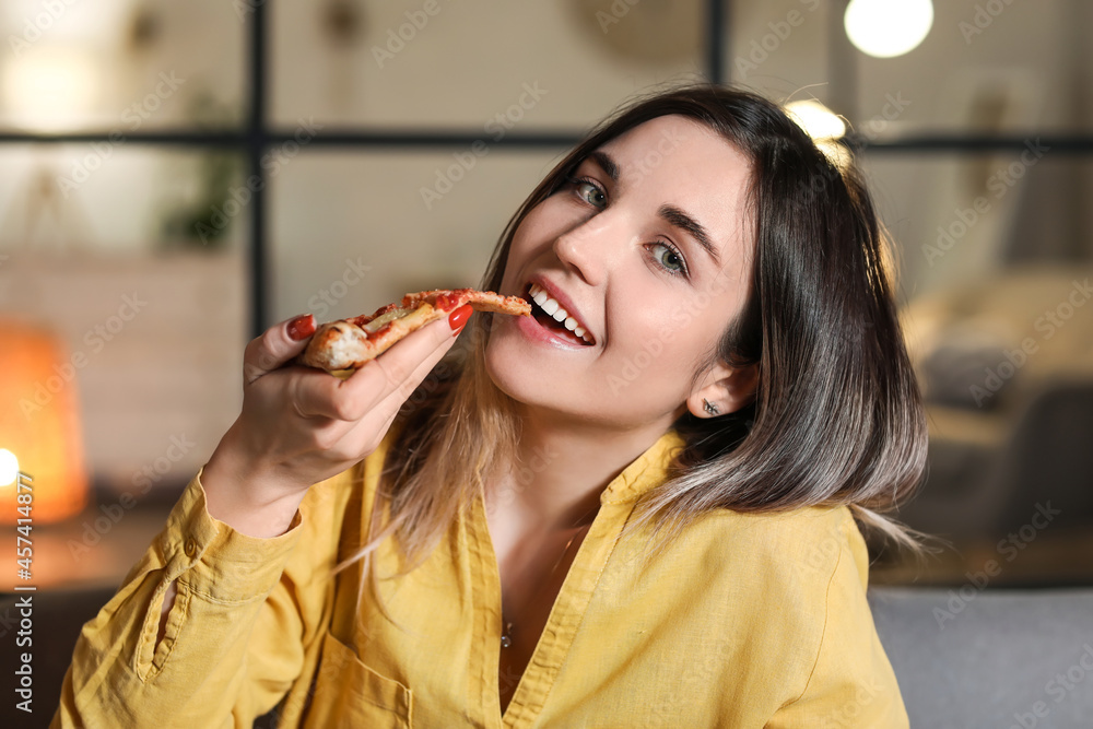 美丽的年轻女子晚上在家吃美味的披萨