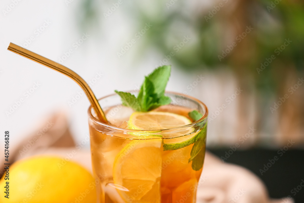 Glass of tasty ice tea with lemon against blurred background, closeup