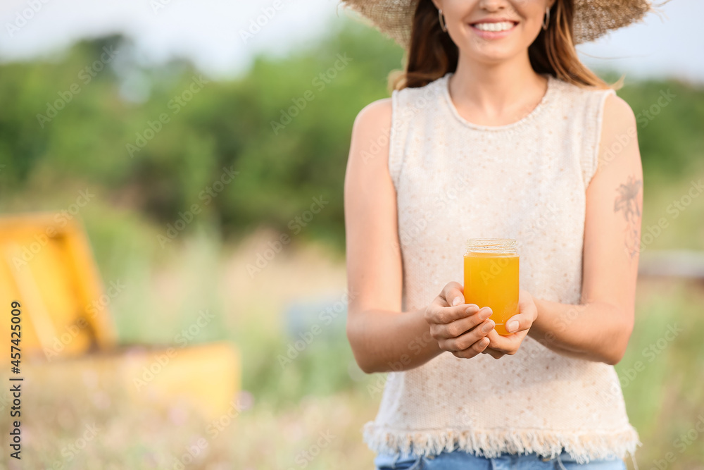 Female beekeeper with sweet honey at apiary