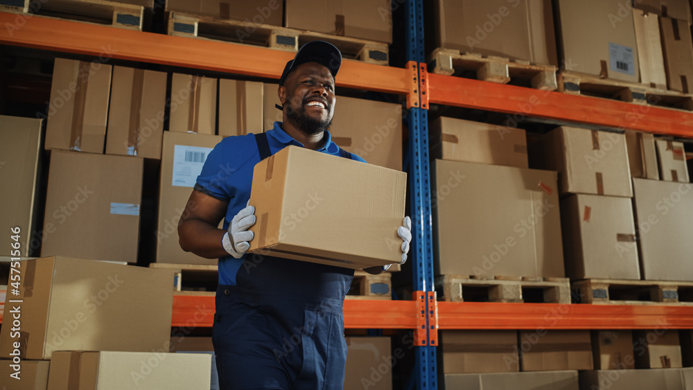 Handsome Black Male Worker Walks Out of Warehouse Carry Cardboard Box and Loads it into Delivery Tru