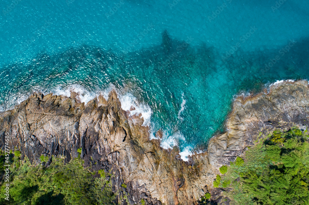 鸟瞰图自上而下，海浪拍打着海岸，阳光明媚，美丽的绿松石海面