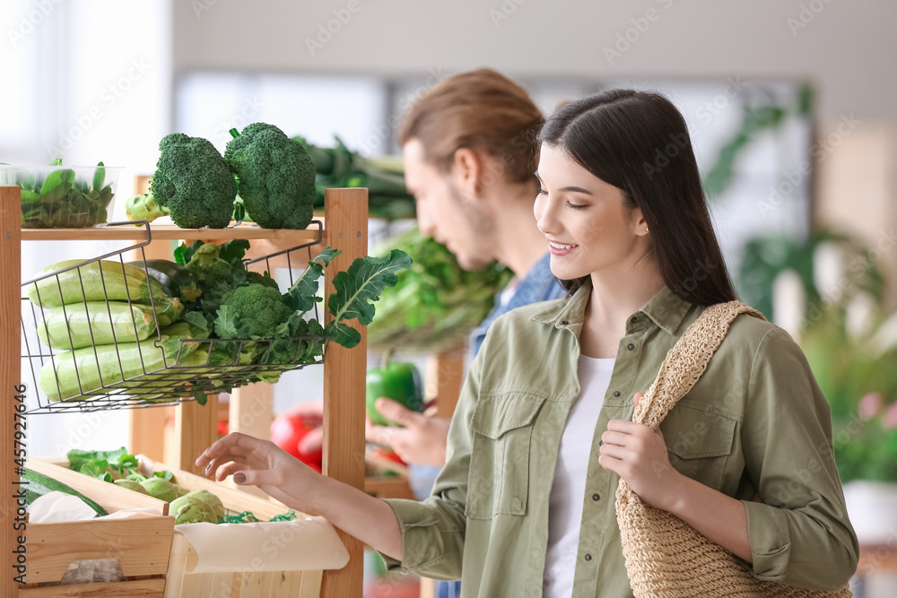 Young woman choosing vegetables in market