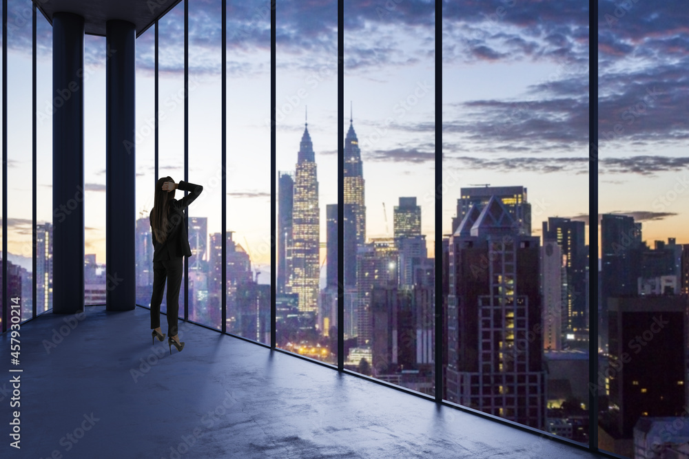 Business woman in empty office looking out of panoramic window with bright city downtown view. Futur