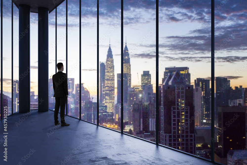 Business man in empty office looking out of panoramic window with bright city downtown view. Future,