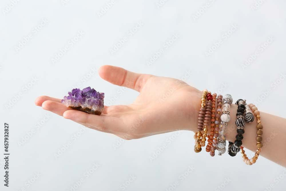 Female hand with beautiful amethyst on light background