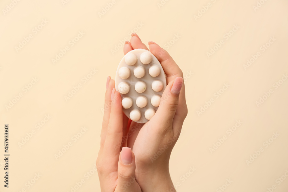 Female hands with massage soap bar on color background