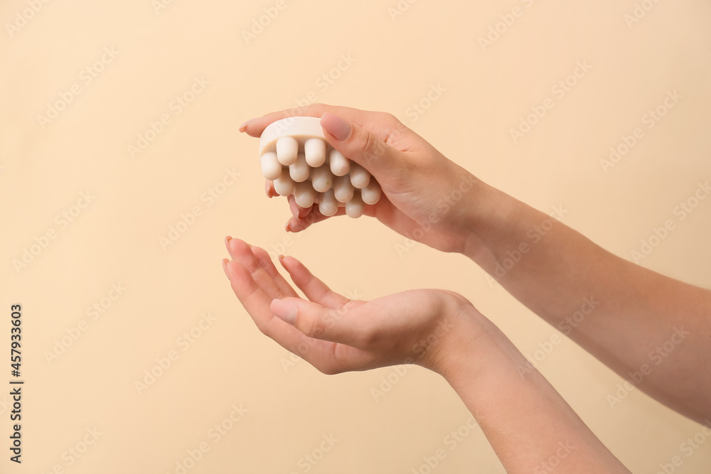 Female hands with massage soap bar on color background