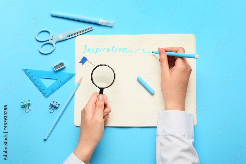 Female hands, stationery supplies and word INSPIRATION on color background