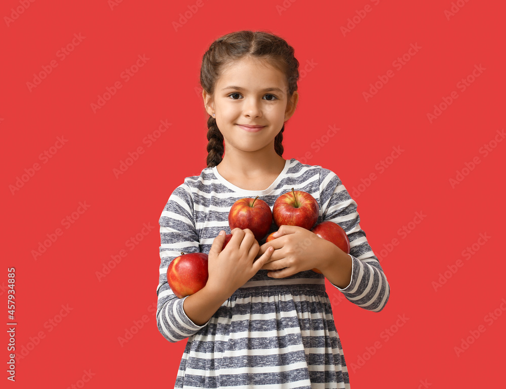 Little girl with apples on color background