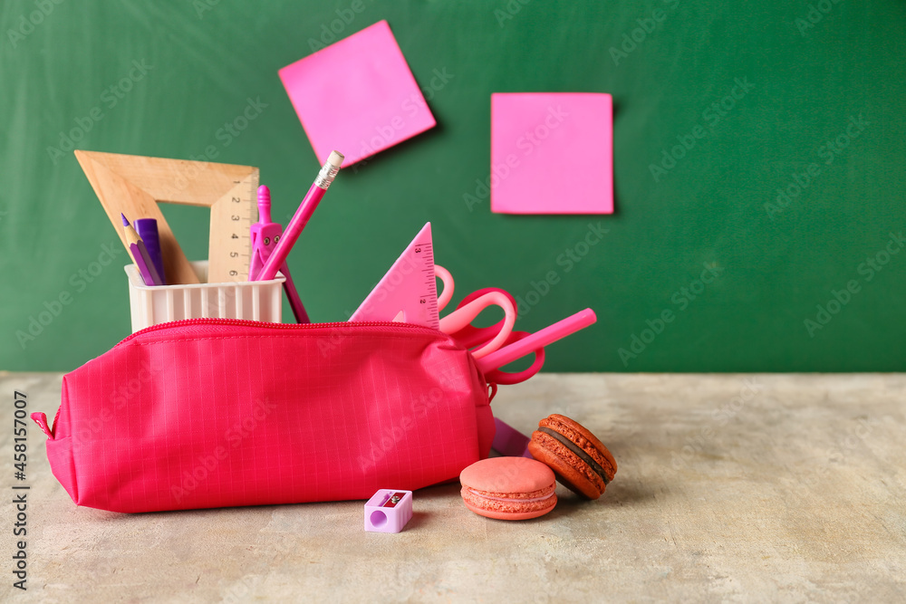 Pencil case with stationery and cookies on table in classroom