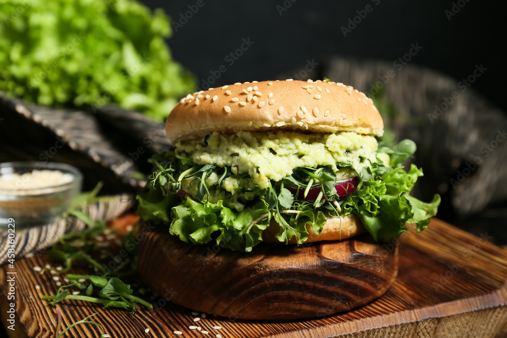 Wooden board with tasty vegetarian burger on table