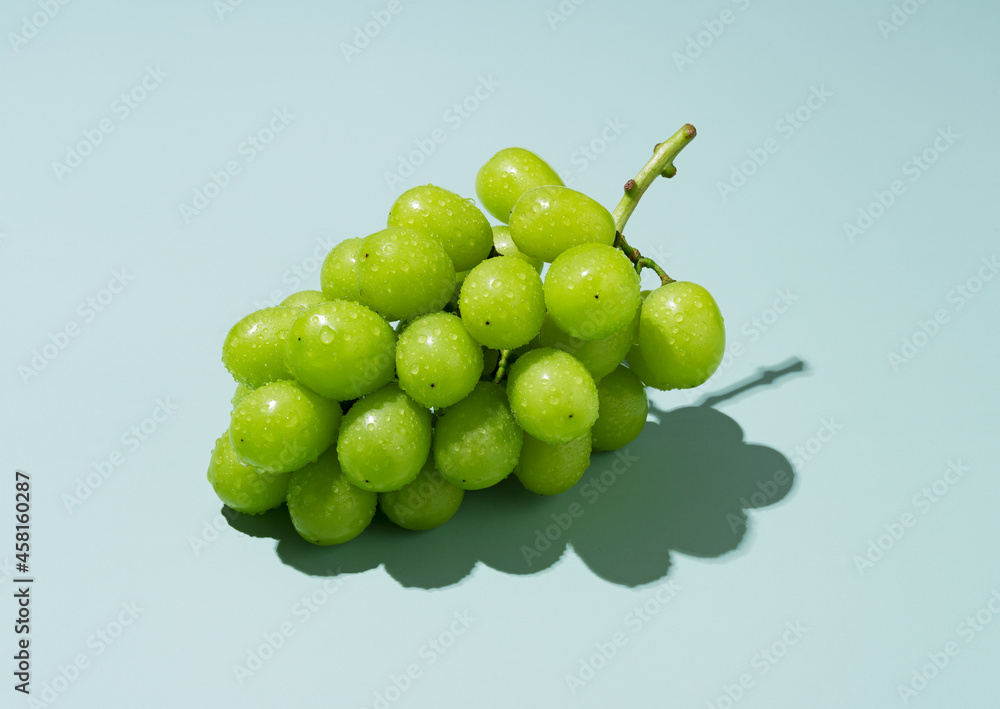 Shine Muscat grapes with water droplets on a green background.