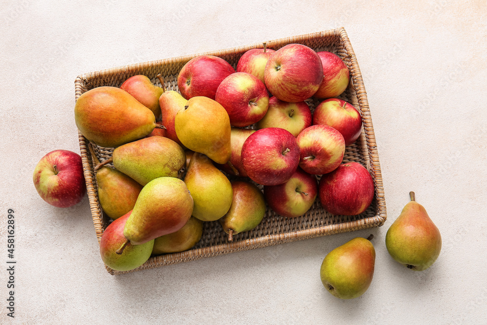 Tray with ripe pears and apples on light background