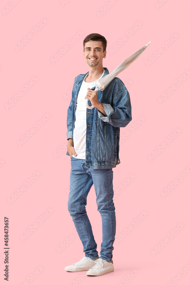 Stylish young man with umbrella on color background