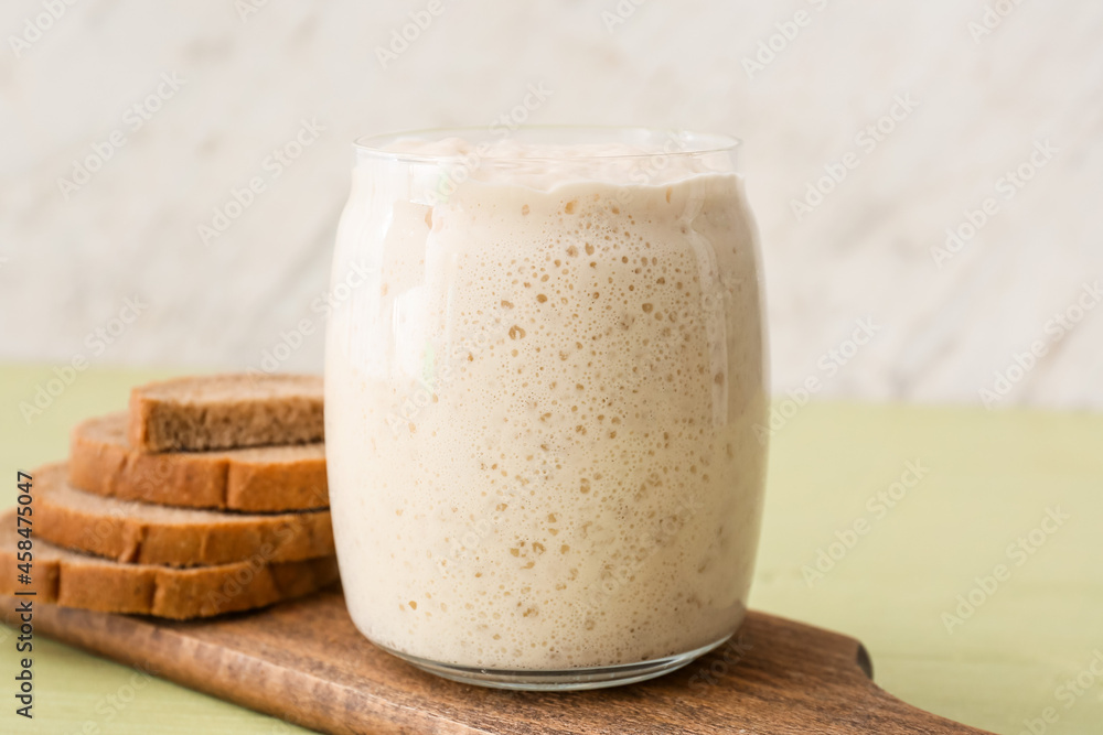 Glass jar with fresh sourdough and bread slices on table