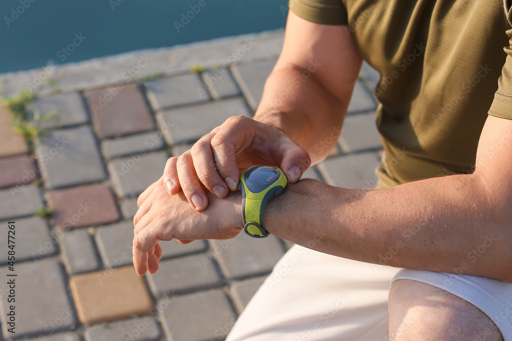 Male runner checking pulse outdoors, closeup