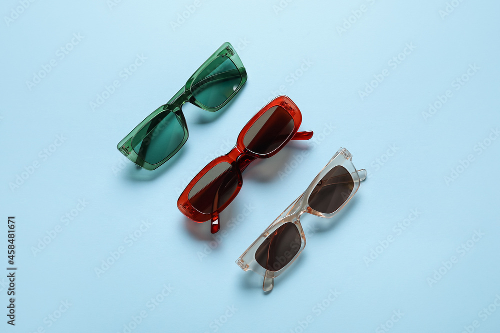 Stylish female sunglasses on color background