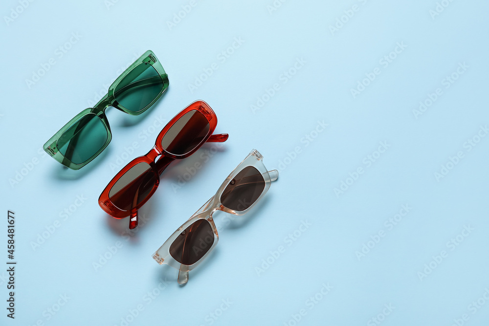 Stylish female sunglasses on color background