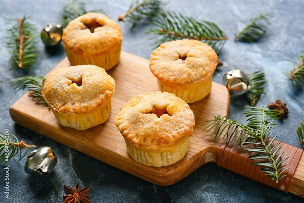 Board with tasty mince pies and Christmas decor on color background