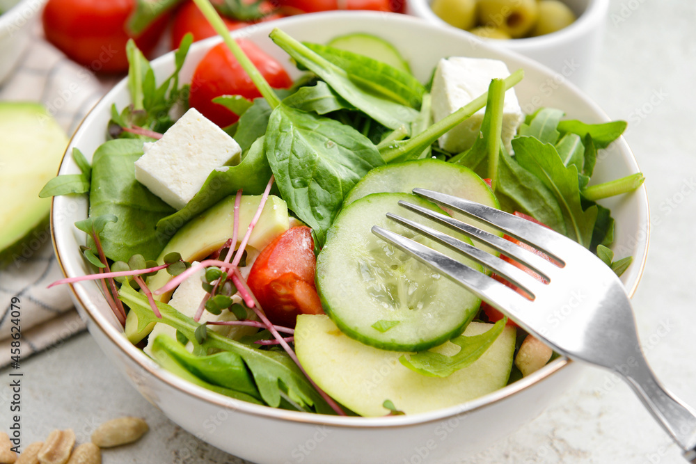 Plate with healthy salad on light background