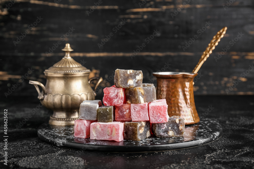 Board with Turkish delight and coffee pot on dark background