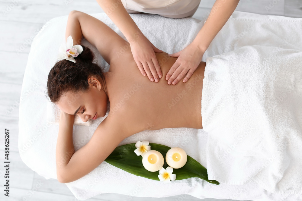 Beautiful young African-American woman getting massage in spa salon