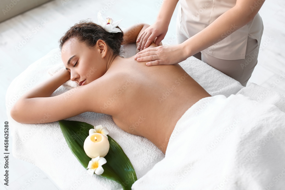 Beautiful young African-American woman getting massage in spa salon