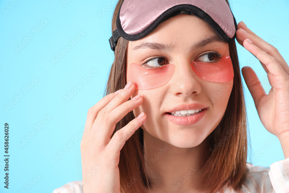 Young woman with under-eye patches on color background