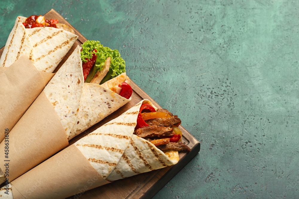 Wooden board with tasty Fajitas on color background, closeup