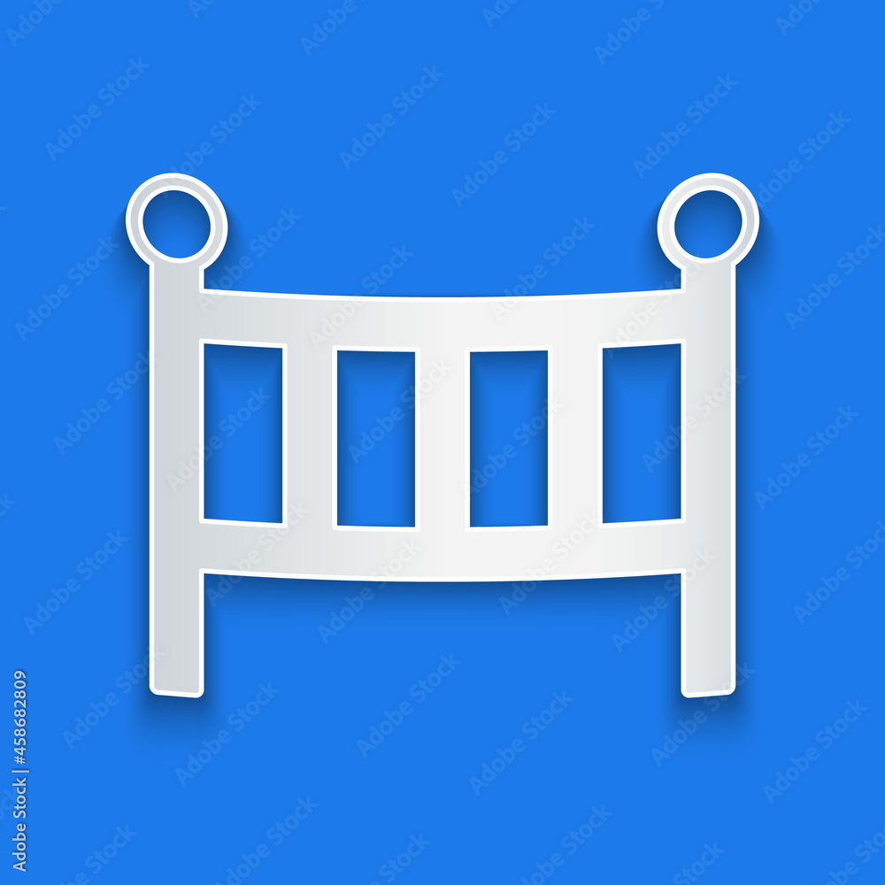 Paper cut Baby crib cradle bed icon isolated on blue background. Paper art style. Vector