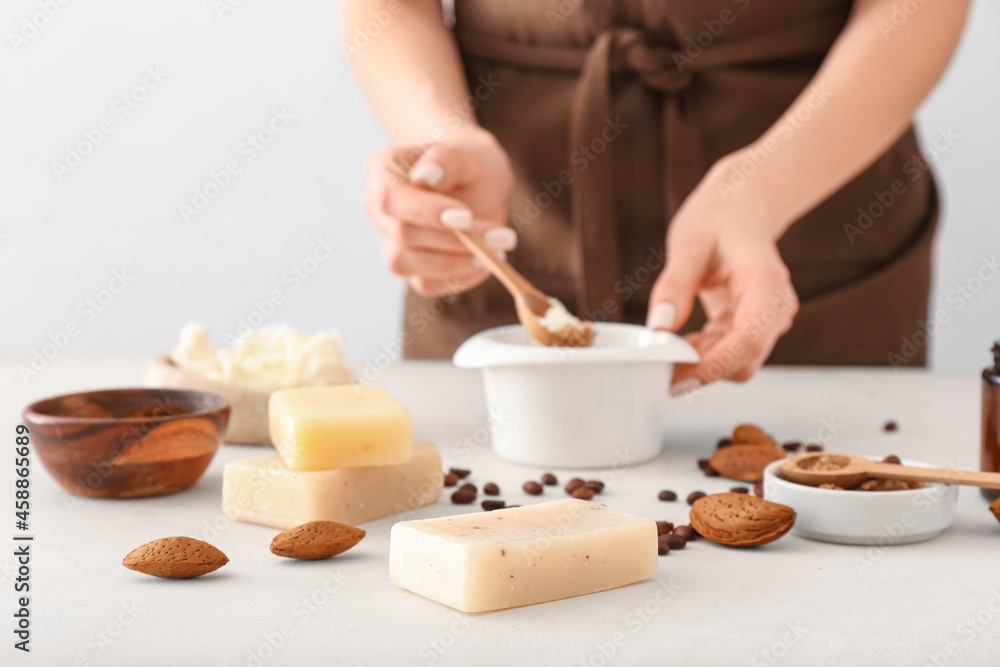 Woman making natural soap on light background