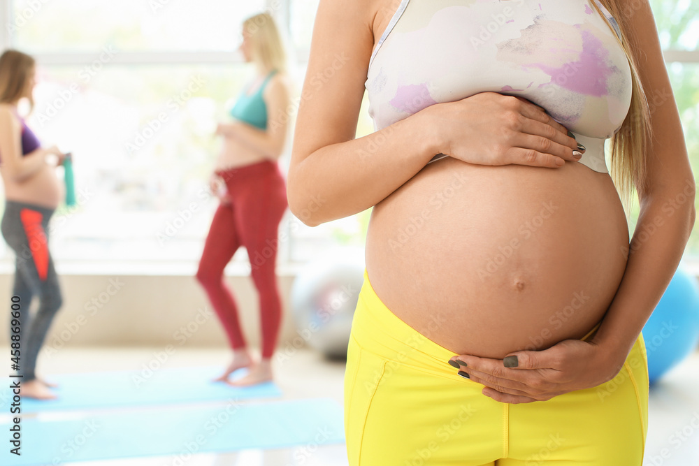 Young pregnant woman at yoga studio, closeup