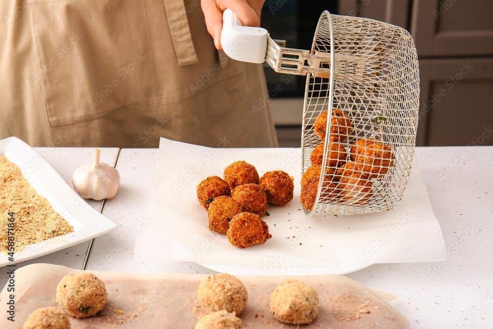 Woman with prepared cod cutlets in kitchen