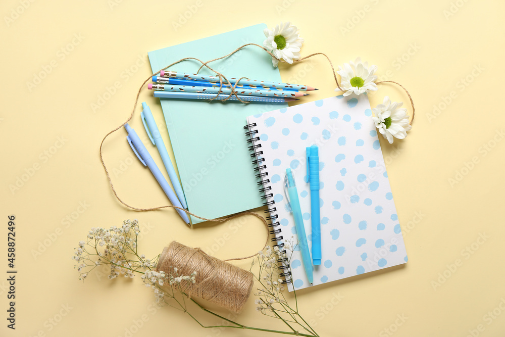 Set of stationery supplies and chamomile flowers on color background