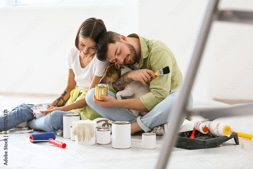 Young couple with cute dog resting during repair of their new house