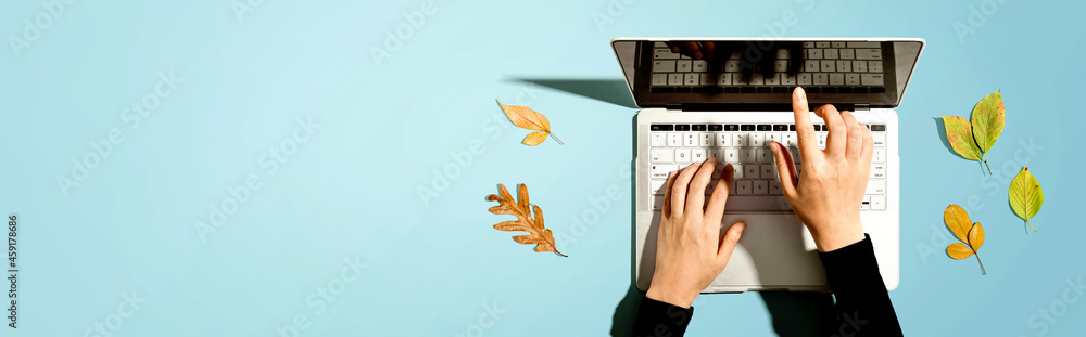 Autumn leaves with person using a laptop computer from above