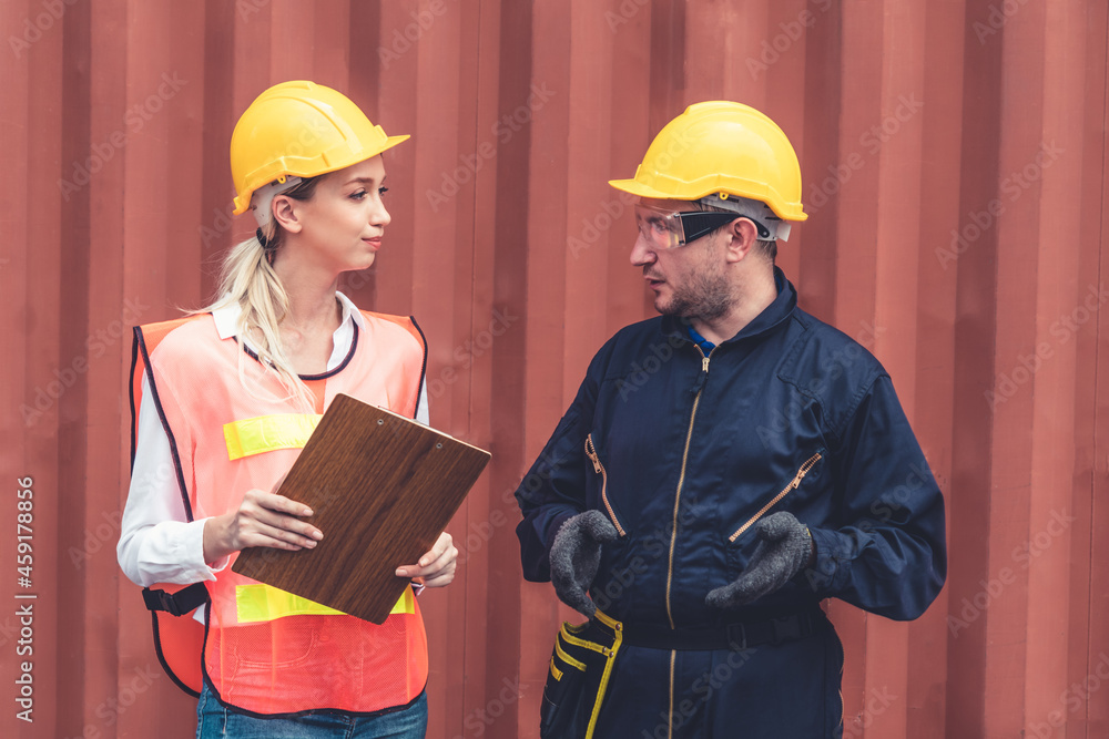 Industrial worker works with co-worker at overseas shipping container yard . Logistics supply chain 