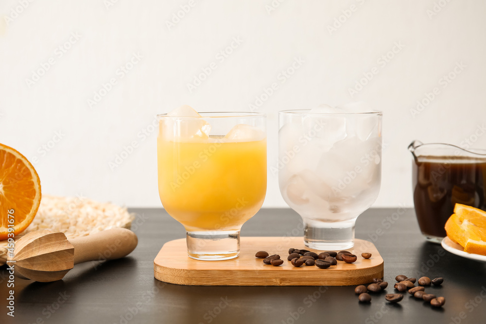 Glass of cold orange juice and coffee beans on table